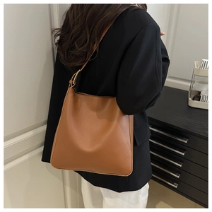 Brown faux leather bucket bag with adjustable strap shown on model in minimal indoor setting
