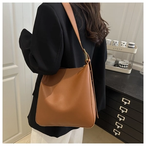 Detailed side view of caramel leather hobo bag with adjustable wide strap and gold hardware