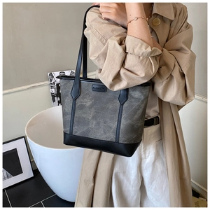 Detail of grey tote bag with leather handles and fashion logo on casual beige trench coat
