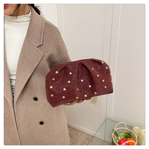 Detail of wine red clutch with animal texture and gold metal studs held by model