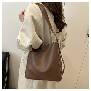 Detail of dark brown leather tote bag with wide shoulder strap and gold metal buckle