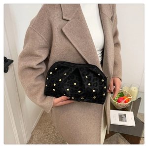 Macro detail of black leopard texture and gold stud rivets on pleated cloud clutch bag