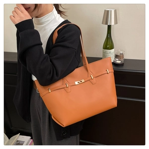 Detail of the orange leather tote bag with gold buckle and adjustable shoulder strap