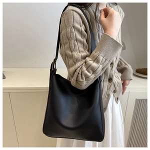 Detail of minimalist black matte leather hobo bag with adjustable strap and gold buckle