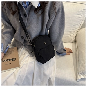 Detail of black nylon crossbody bag with metal logo and adjustable shoulder strap