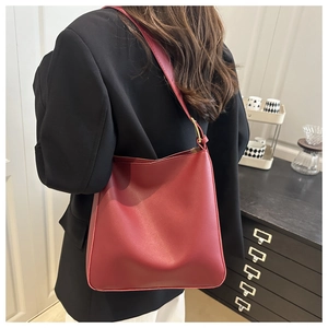 Detail of a deep red minimalist tote bag in matte synthetic leather on shoulder