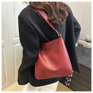 Detailed back view of a dark red minimalist bucket bag on a model in a modern home setting