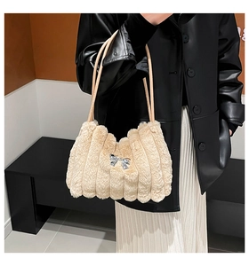 Détail du sac à épaule en fausse fourrure beige avec matelassage et nœud argenté