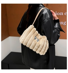 Gros plan du sac en peluche beige avec nœud argenté et rayures verticales matelassées