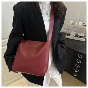 Detail of burgundy leather crossbody bag featuring minimalist design and wide shoulder strap