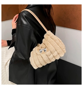 Detail view of beige plush shoulder bag featuring vertical texture and silver bow charm