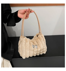 Détail du sac à main crème en peluche avec texture verticale et nœud métallique argenté