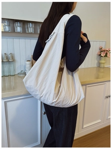 Detail of a large cream hobo shoulder bag with zipper and relaxed crescent shape