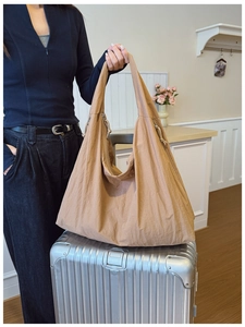 Detail of a large brown nylon tote bag with zipper on a silver suitcase for travel