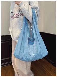 Detail of light blue crescent shoulder bag featuring ruched texture and wide strap