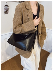 Side view of a black high-capacity faux leather hobo tote bag worn by a model