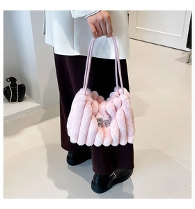 Gros plan du sac en fausse fourrure rose avec plis verticaux et pendentif nœud argenté