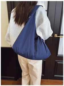 Rear view of a model wearing the large navy blue nylon shoulder bag with a relaxed design