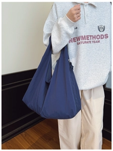 Detail of a large navy tote bag showing drape and spacious capacity on a model