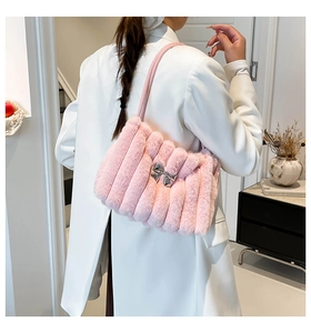 Détail du sac à épaule en fausse fourrure rose avec nœud argenté sur blazer blanc