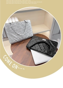 Quilted butterfly pattern laptop bag with metallic finish and top handle on a table