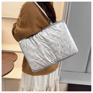 Detail of silver quilted laptop bag with 3D bow texture and adjustable shoulder strap