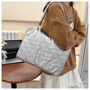 Silver quilted tote laptop bag with bow pattern and shoulder strap shown on model