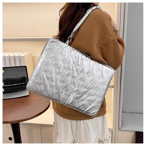 Detailed view of silver quilted laptop sleeve with bow patterns and fashion woven label