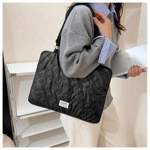 Detail of black quilted laptop bag featuring embossed 3D bow patterns and fashion label