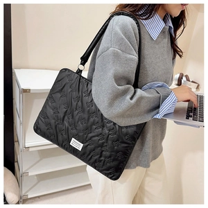 Detail of black quilted laptop bag featuring elegant bow patterns and fashion label