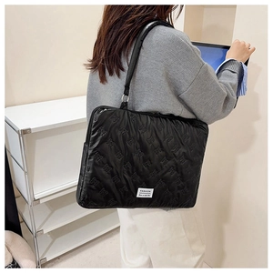 Detail of black quilted laptop bag featuring elegant butterfly patterns and fashion label