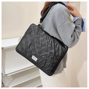 Detailed view of black quilted laptop bag with ribbon texture and fashion label