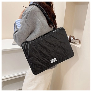 Close-up of black quilted laptop bag with 3D bow patterns and adjustable shoulder strap