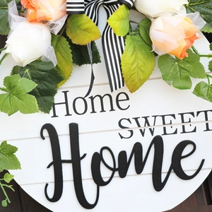 Round wooden welcome sign with Home Sweet Home text, faux roses, and a striped bow