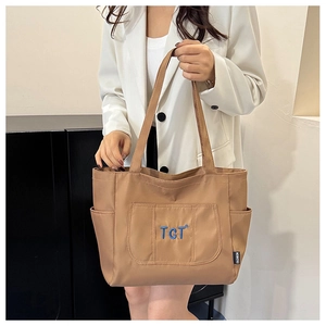 Détail du sac fourre-tout marron avec broderie TGT et étiquette mode sur la poche