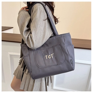 Détail du sac fourre-tout gris foncé avec logo doré et poches latérales pratiques