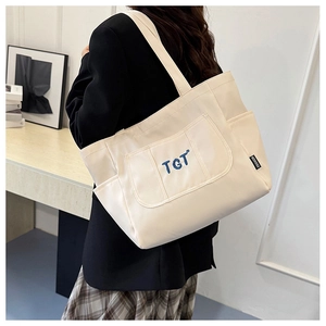 Détail du grand sac cabas en toile beige avec broderie TGT bleue et étiquette mode