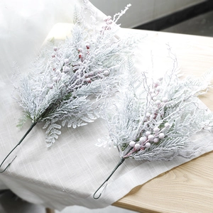 Snow-flocked Christmas pine branches with red berries for winter holiday floral decor