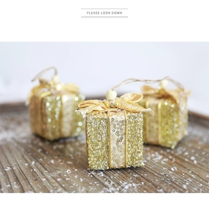 Nahaufnahme goldener Glitzer-Geschenkbox-Anhänger mit Schleifen auf Holztablett