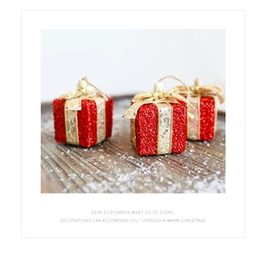 Nahaufnahme glitzernder roter Weihnachtsgeschenkbox-Anhänger mit Goldbändern und Holzperlen