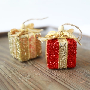 Glitzernde Weihnachts-Geschenkboxen mit goldenen Bändern und Holzperlen auf Holztablett