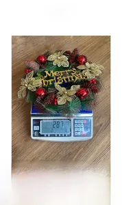 Vue détaillée d'une couronne de Noël de 30cm avec boules rouges et pommes de pin sur balance