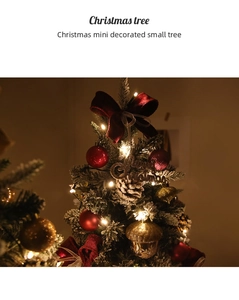 Close-up of a mini flocked Christmas tree with red velvet bows, pine cones and LED lights