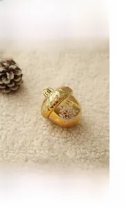 Close-up of golden acorn Christmas ornament with white snowflakes on warm plush background