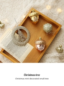 Silver glitter tree ornament and acorn pendants with snowflake patterns on wood tray