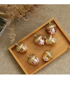 Close-up of six acorn Christmas ornaments with snowflake patterns on a wooden tray