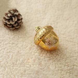 Golden acorn Christmas ornament with white snowflakes on soft white faux fur background
