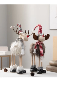 Nahaufnahme von Plüsch-Weihnachtselchen mit Strickschals und leuchtenden Details