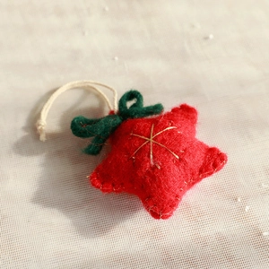 Close-up of red wool felt star ornament with green bow and gold embroidery details