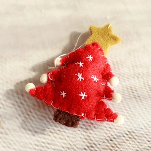 Macro view of red wool felt Christmas tree ornament with white snowflakes and star